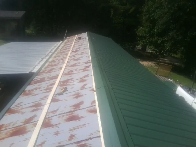 Old rusted panels beside newly installed green metal roofing — Wind Damage Roof Repair by Roofing Brothers in Danbury