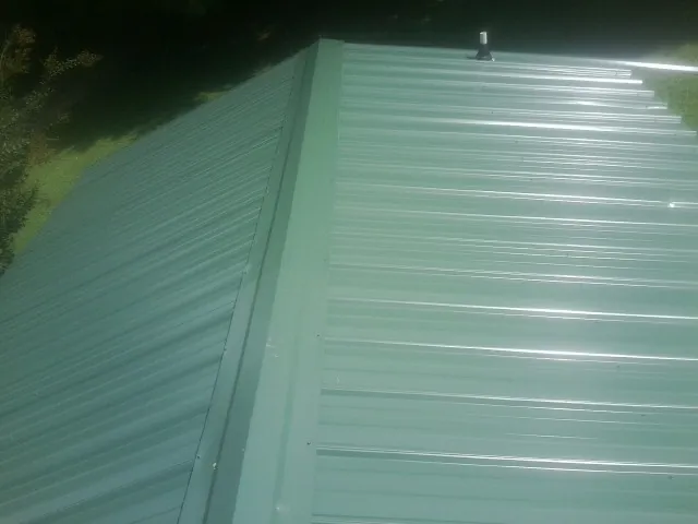 New green metal panels meeting at the ridge of a roof — Flat Roof Repair work by our crew in Danbury