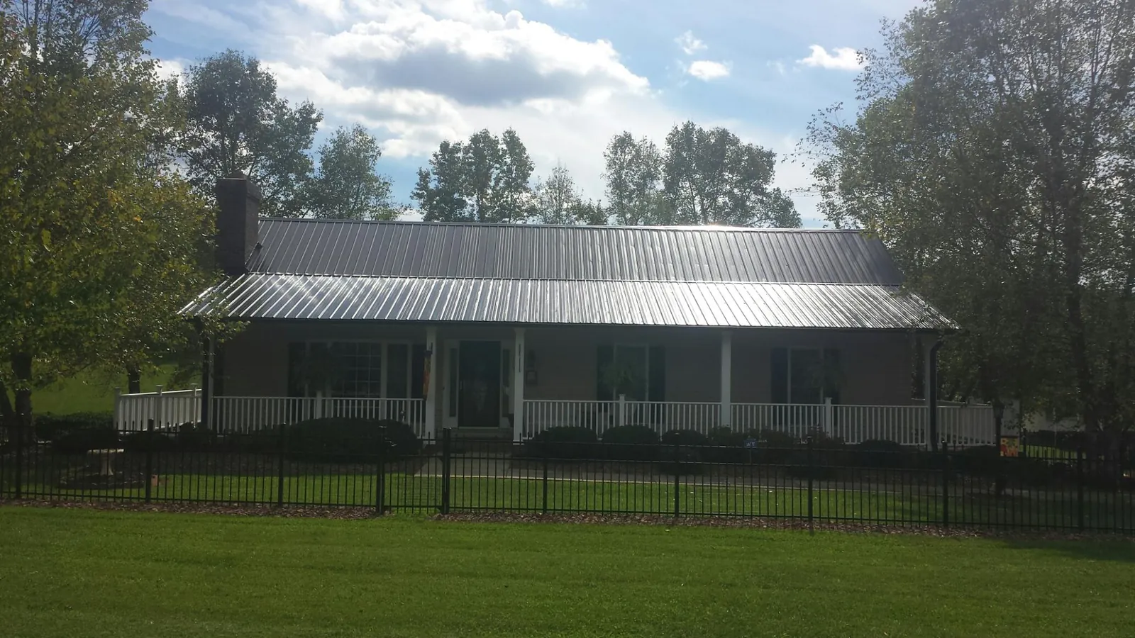 Gray metal roof on a brick ranch with a full width front porch — Gutter Guard Installation work by our crew in Danbury