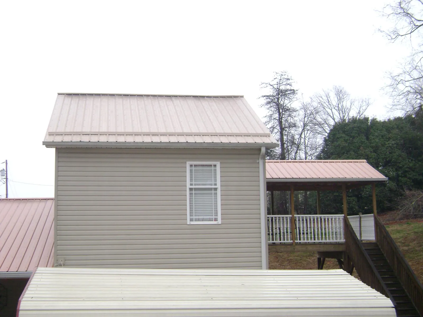 Tan metal roofs on a two story addition and attached porch, from a Roof Replacement job in Danbury
